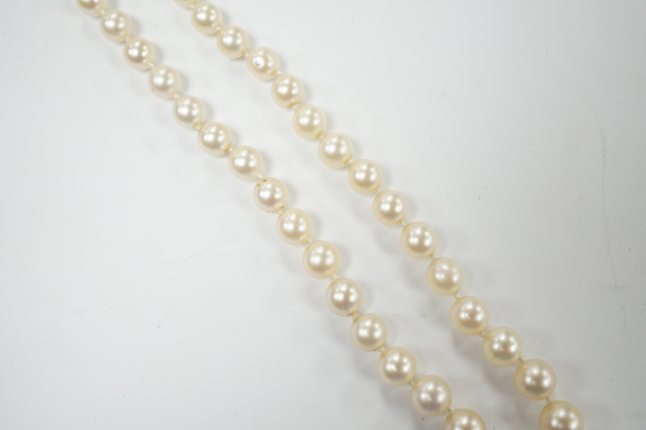 A single strand graduated cultured pearl necklace, with three stone diamond set white metal clasp, 44cm, Fair condition.